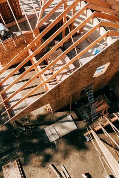 Workers build the frame of a new house project.  Bare plywood and beams as it is framed up from the foundation.  High lumber costs have affected the building process.  Shot in Washington state, USA.